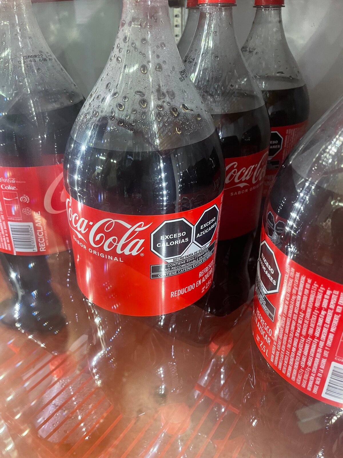 Bouteilles de Coca Cola munies des &eacute;tiquettes noires annon&ccedil;ant "Exc&egrave;s de calories, Exc&egrave;s de sucres", gr&acirc;ce &agrave; l'action d'associations, Mexico, f&eacute;vrier 2022. Photo: &copy; P.Bickel