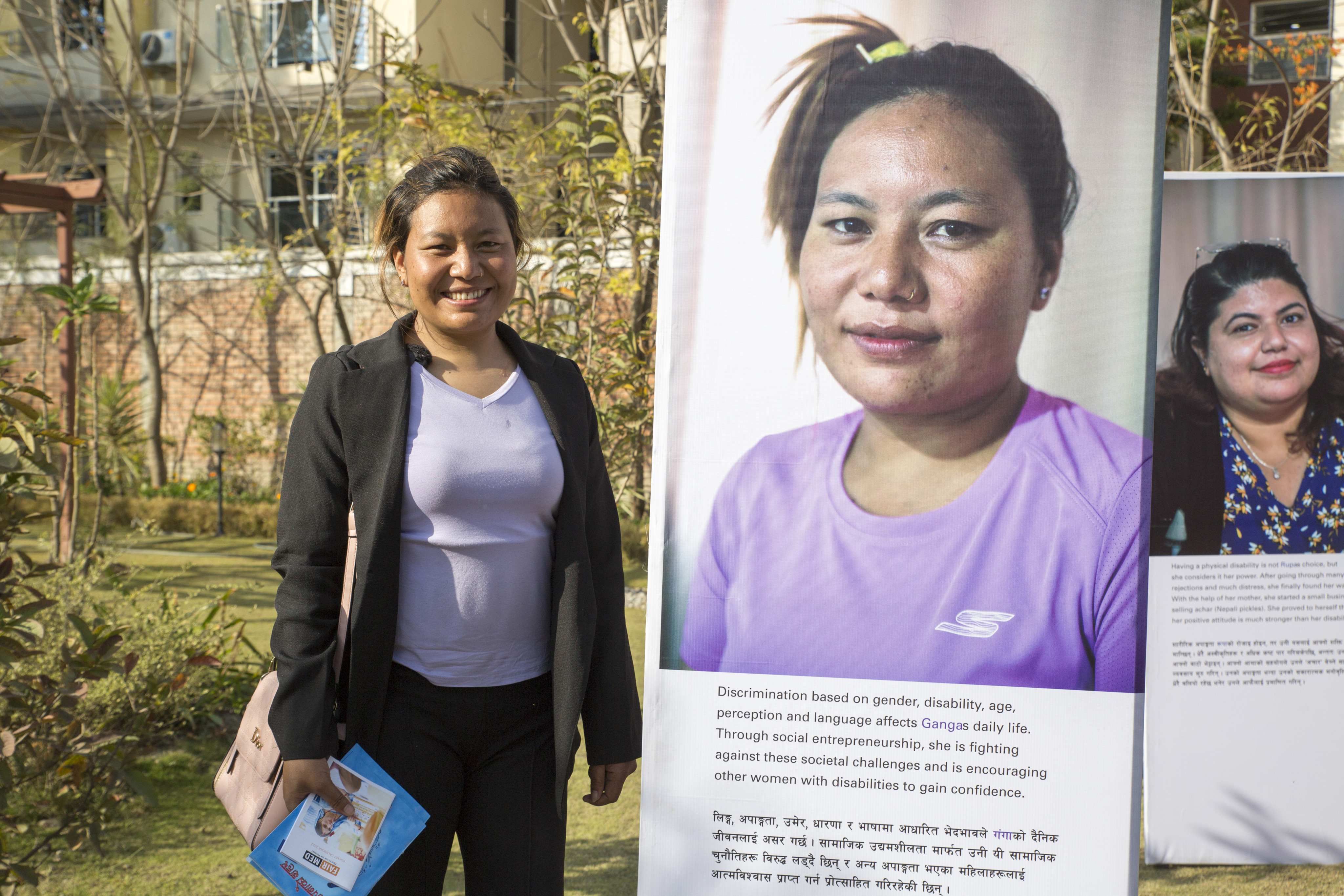 A Photovoice participant stands next to her portrait during the opening of the exhibition in Nepal. Photo: &copy; CBM <br>