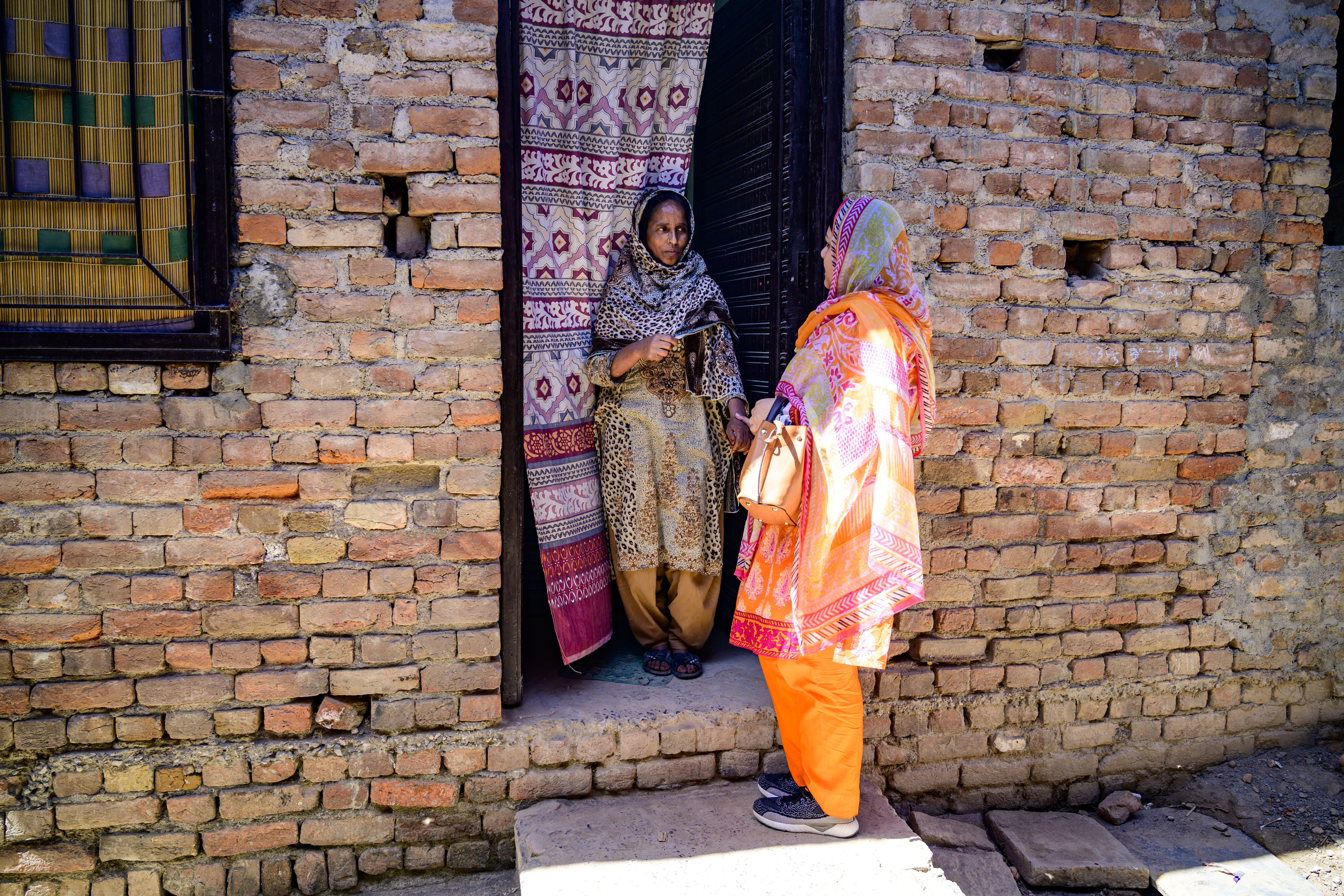 Islamabad, Pakistan - 5 May, 2019: Health worker speaking with the mother of a man with disabilities in the entrance of the family house during a field assistive technology survey for persons with disabilities in the outskirts of Islamabad. Photo: &copy; WHO / NOOR / Sebastian Liste <br>